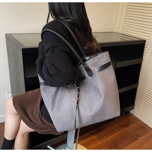 Detailed side view of large grey tote bag with black handles and metal buckle accents