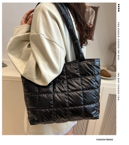 Detail of a large black quilted tote bag with square lattice pattern and wide strap