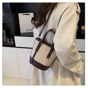 Detail of vintage beige canvas bucket bag with dark brown leather handle and trim