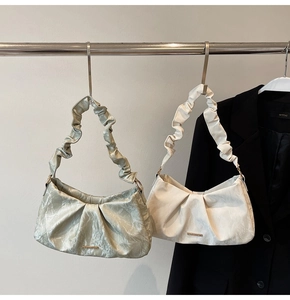 Close-up of pleated leather shoulder bag with scrunchie handle and pearlescent finish