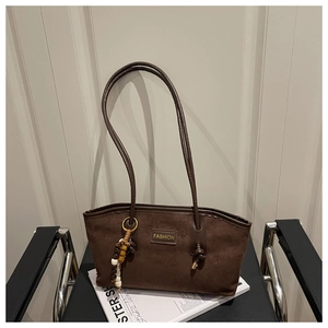 Close-up of dark brown suede tote bag featuring a Fashion label and beaded charm detail