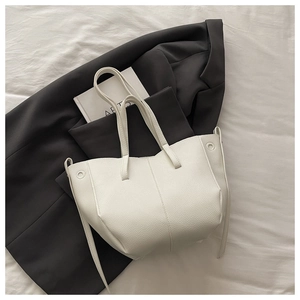 Detail view of white lychee texture tote bag on grey blazer for a modern office look