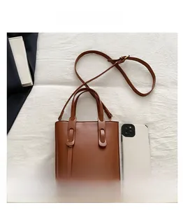 Brown minimalist tote bag with top handles and shoulder strap shown with phone for size reference
