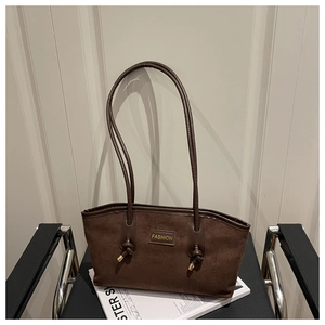 Detailed close-up of dark brown suede tote bag with metal knot accents and fashion tag