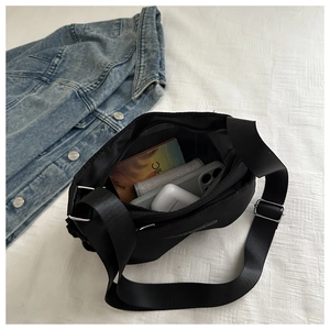 Internal compartments of black nylon crossbody bag showing storage space for phone