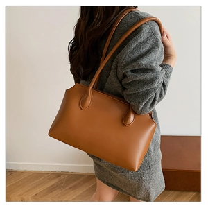 Brown leather tote bag detail showing shoulder strap attachment and material texture