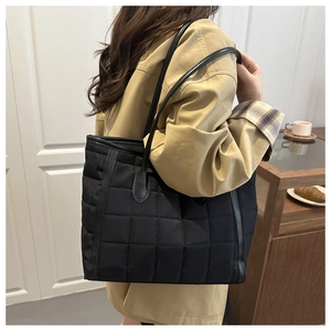 Detailed view of a black quilted tote bag with leather straps for daily commute