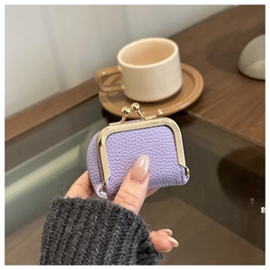 Close-up of a mini purple lychee leather coin purse with golden metal clasp closure