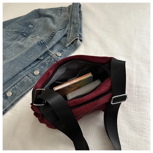 Close-up of wine red nylon crossbody bag showing multiple zippered storage compartments
