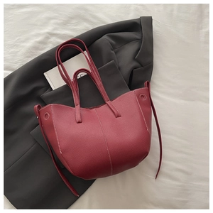 Close-up of burgundy lychee leather bucket bag with white contrast stitching detail