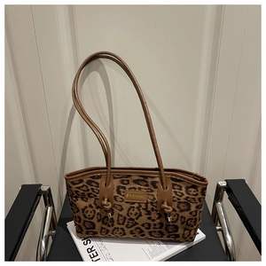Close-up of leopard print suede tote with leather straps on a modern black chair