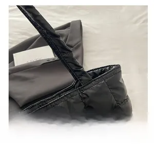 Macro shot of black quilted nylon texture and padded handle on a chic tote bag