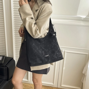 Detail of black large tote bag with vintage texture and white brand lettering on shoulder