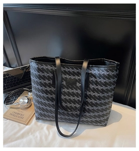 Macro shot of large tote bag featuring grey geometric patterns and leather handles