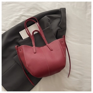 Detail of burgundy bucket bag featuring white contrast stitching and lychee leather texture