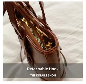 Detail of dark brown leather bag showing gold detachable hook and secure zipper closure