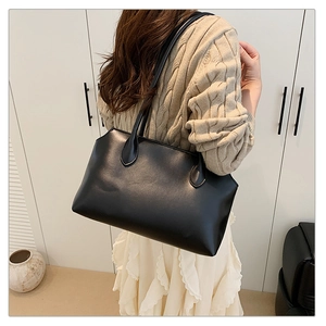 Minimalist black faux leather tote bag worn with beige sweater and white skirt