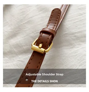 Close-up of adjustable brown leather handbag strap with polished gold buckle and fine stitching