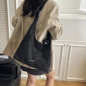 Minimalist black oversized tote bag in matte leather featuring hollow-out design