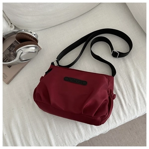 Detail of dark red water-resistant nylon crossbody bag with adjustable black strap
