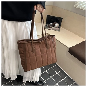 Detailed view of brown quilted tote bag with large square stitching and dual shoulder straps