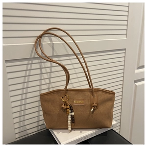 Close-up detail of brown suede tote bag with fashion tag and wooden bead charm