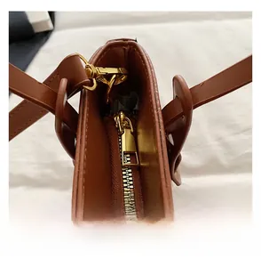 Detail of a smooth golden metal zipper on a premium brown leather bucket handbag