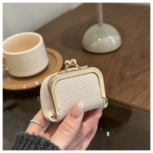 Close-up of a beige lychee leather mini jewelry pouch with a golden kiss-lock clasp