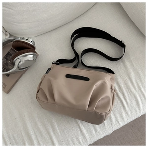 Detail view of khaki nylon crossbody bag with adjustable strap on knit fabric