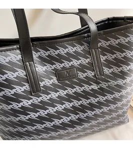 Close-up of pebble grain leather texture and brand logo tag on black printed tote bag