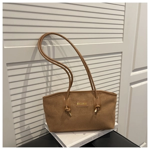 Detailed macro view of the gold metal plate and brown suede fabric on the shoulder bag