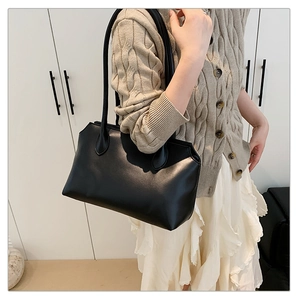 Side view of black matte leather tote bag with wavy top edge and slim straps on model
