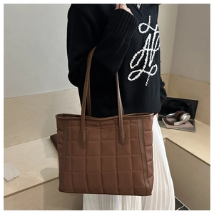 Macro detail of large brown quilted tote bag with long double handles for shoulder wear