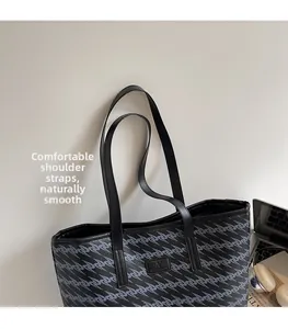 Detail of large tote bag showing black geometric wave pattern and leather shoulder straps