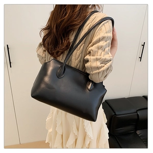 Rear view of model wearing a black leather tote bag with long straps on one shoulder