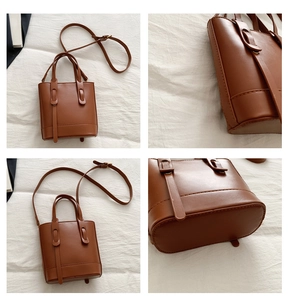 Detail view of brown faux leather bucket bag showing handles, stitching and base texture