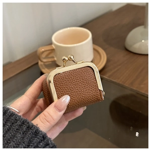 Macro detail of mini brown pebbled leather pouch with a golden ball clasp closure