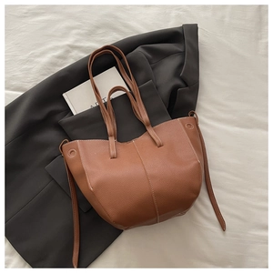 Close-up of caramel brown pebble leather tote bag with white contrast stitching details