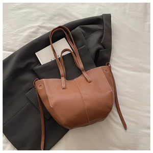 Close-up of brown bucket bag showing pebbled leather texture and white contrast stitching