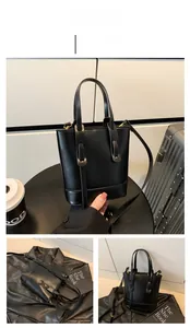 Detailed close-up of a black textured leather bucket bag with top handle and strap