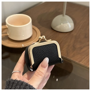 Close-up of a mini black lychee leather coin purse with golden metal clasp
