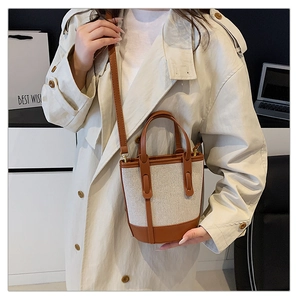 Detail of canvas bucket bag with brown leather trim and adjustable crossbody strap
