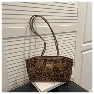 Detail view of leopard print tote bag with brown straps and fashion metal logo