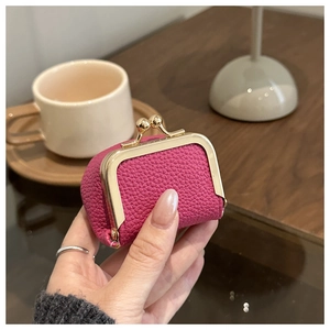 Mini rose red leather coin purse with gold metal clasp closure held in a hand