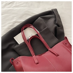 Detail of burgundy lychee grain leather tote bag with white contrast stitching
