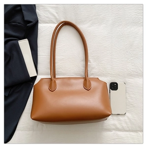 Brown leather tote bag size comparison with smartphone on soft white fabric background