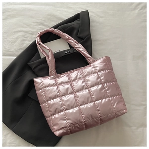 Detail of pink quilted tote bag with metallic finish and soft padded texture on white fabric