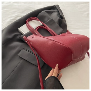 Detail of red leather tote bag featuring white contrast stitching on a grey blazer