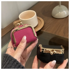 Close-up of luxury lychee grain leather mini coin purses held in hand for scale