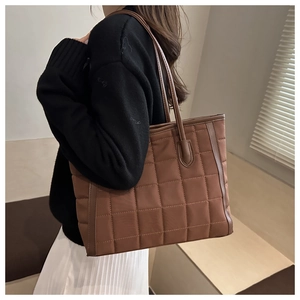 Brown quilted tote bag showing large square padding and spacious side profile on shoulder